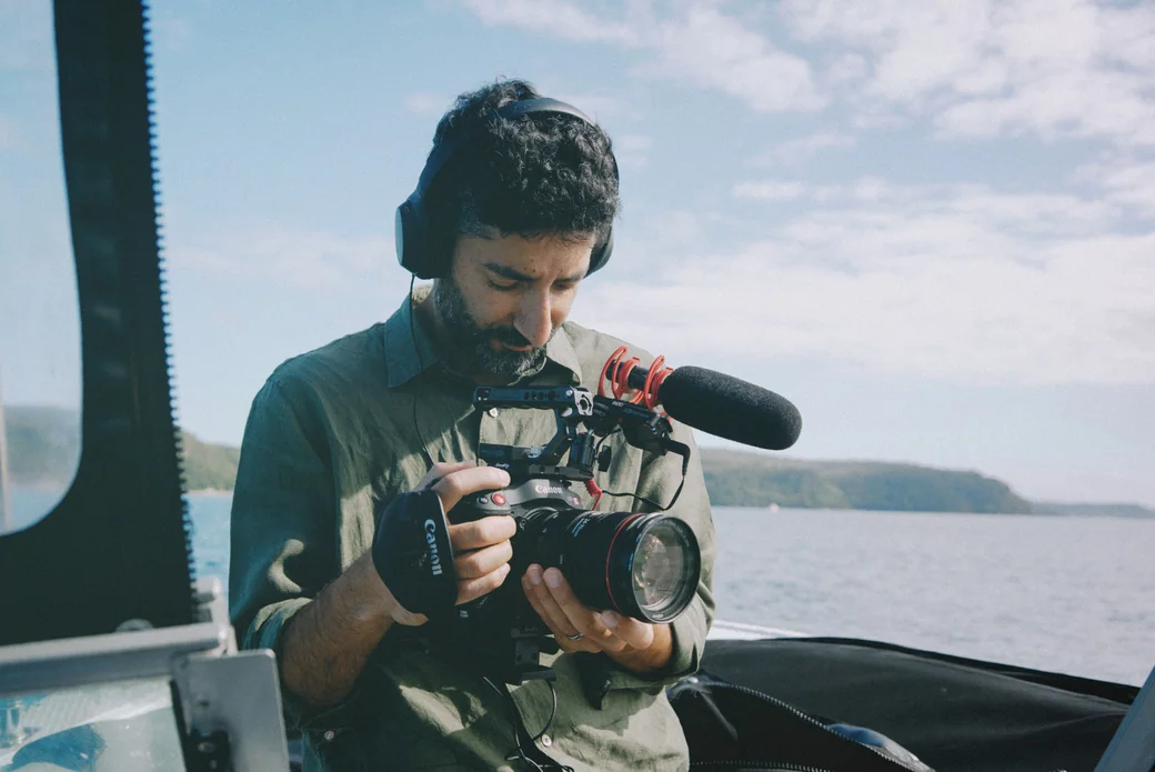 A filmmaker checking his camera while travelling on the water