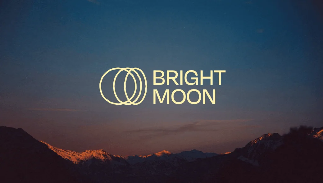 Bright Moon logo over a mountain landscape at dusk