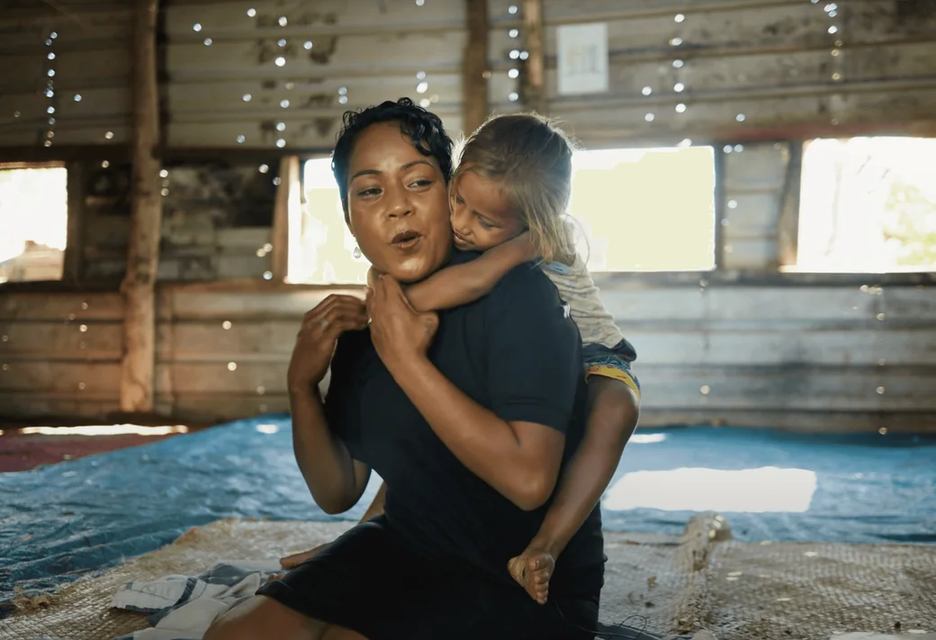 A storyteller holding a child in a grassroots community setting